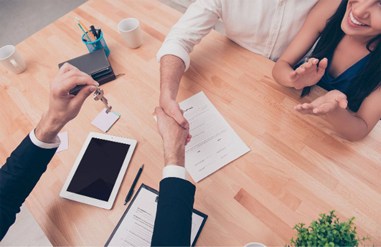 Agente inmobiliario entregando llaves de una propiedad